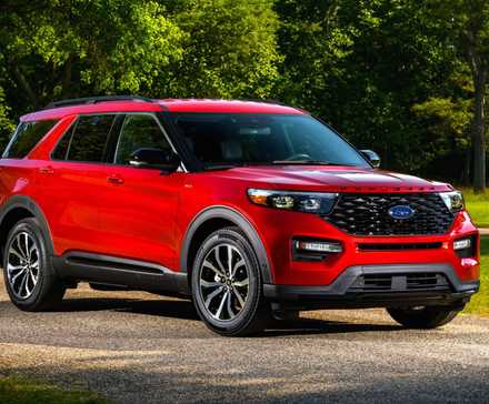 Front three-quarter view of a red 2022 Ford Explorer parked on gravel with trees in the background.
