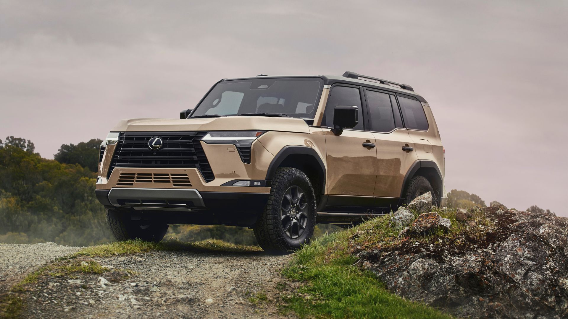 Front three-quarter view of a gold 2024 Lexus GX off-roading.