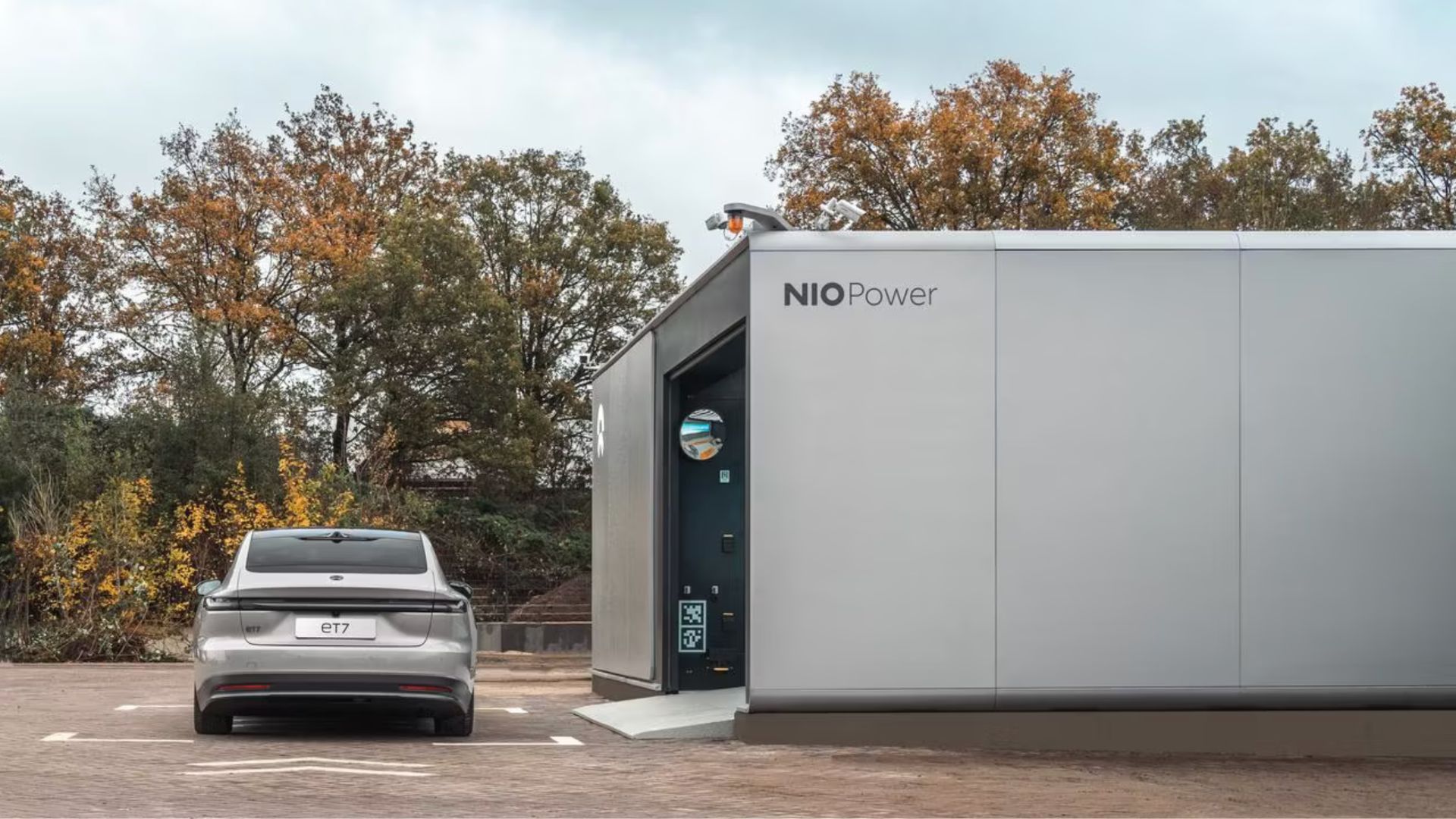 A NIO Power EV battery swapping station with a NIO ET7 parked outside.