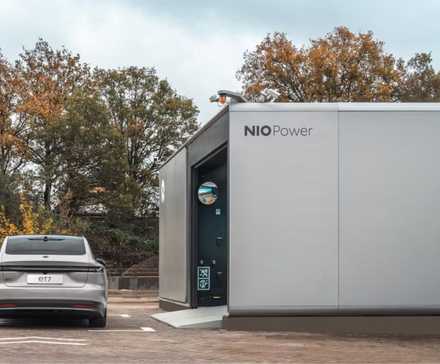 A NIO Power EV battery swapping station with a NIO ET7 parked outside.