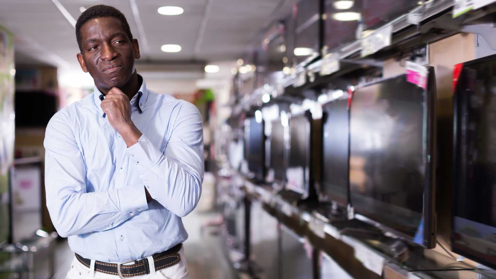 A man chooses a TV set in store of household appliances  