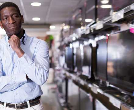 A man chooses a TV set in store of household appliances