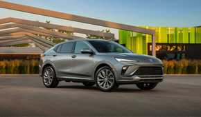 Front 3/4 shot of a gray 2024 Buick Envista Avenir parked with modern architecture in the background.