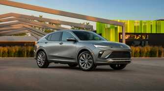 Front 3/4 shot of a gray 2024 Buick Envista Avenir parked with modern architecture in the background.