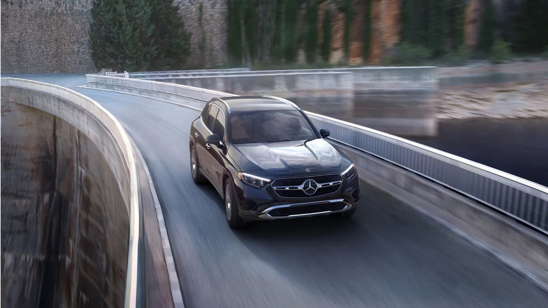 Dynasmic front 3/4 shot of a black 2025 Mercedes-Benz GLC driving over a bridge.
