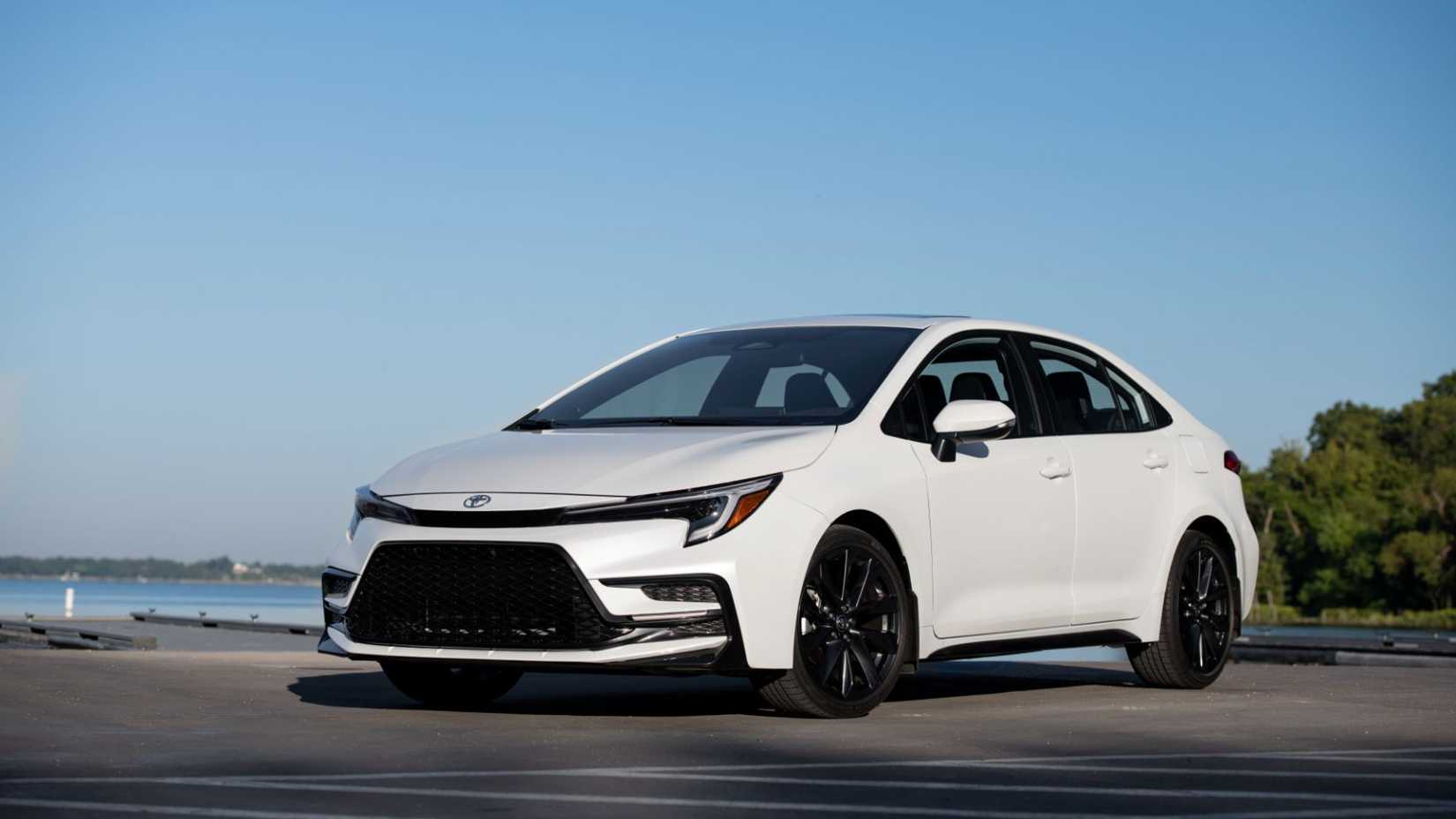 Front 3/4 view of a white 2025 Toyota Corolla Sedan parked with the ocean in the background.