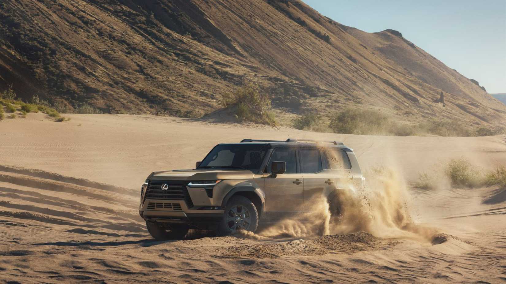 Front 3/4 view of a gold 2025 Lexus GX off-roading in the sand.