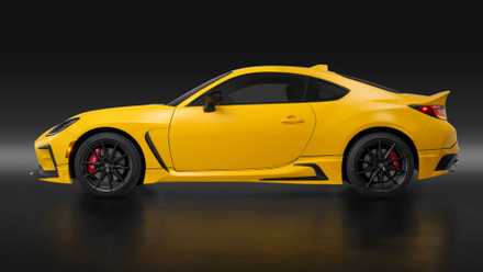Side profile shot of a yellow 2026 Toyota GR86 Yuzu in a studio with a black backdrop.