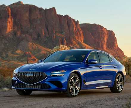Front 3/4 shot of a blue 2025 Genesis G70 parked on gravel with a mountain in the background.