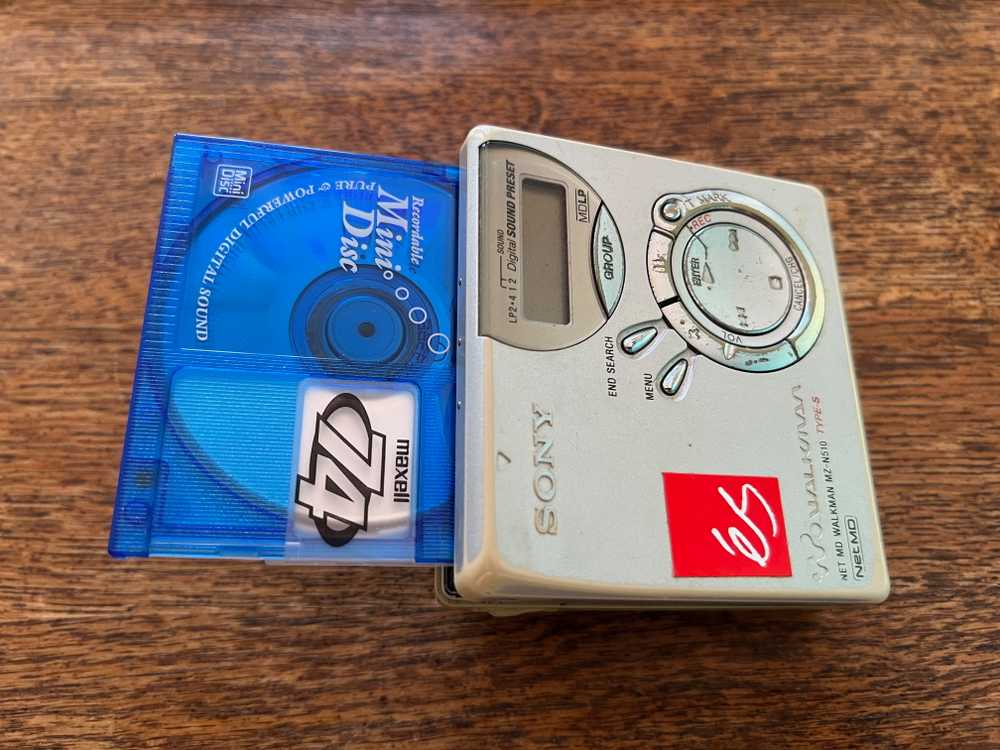 A MiniDisc partially ejected from a portable player, showing the format's compact design