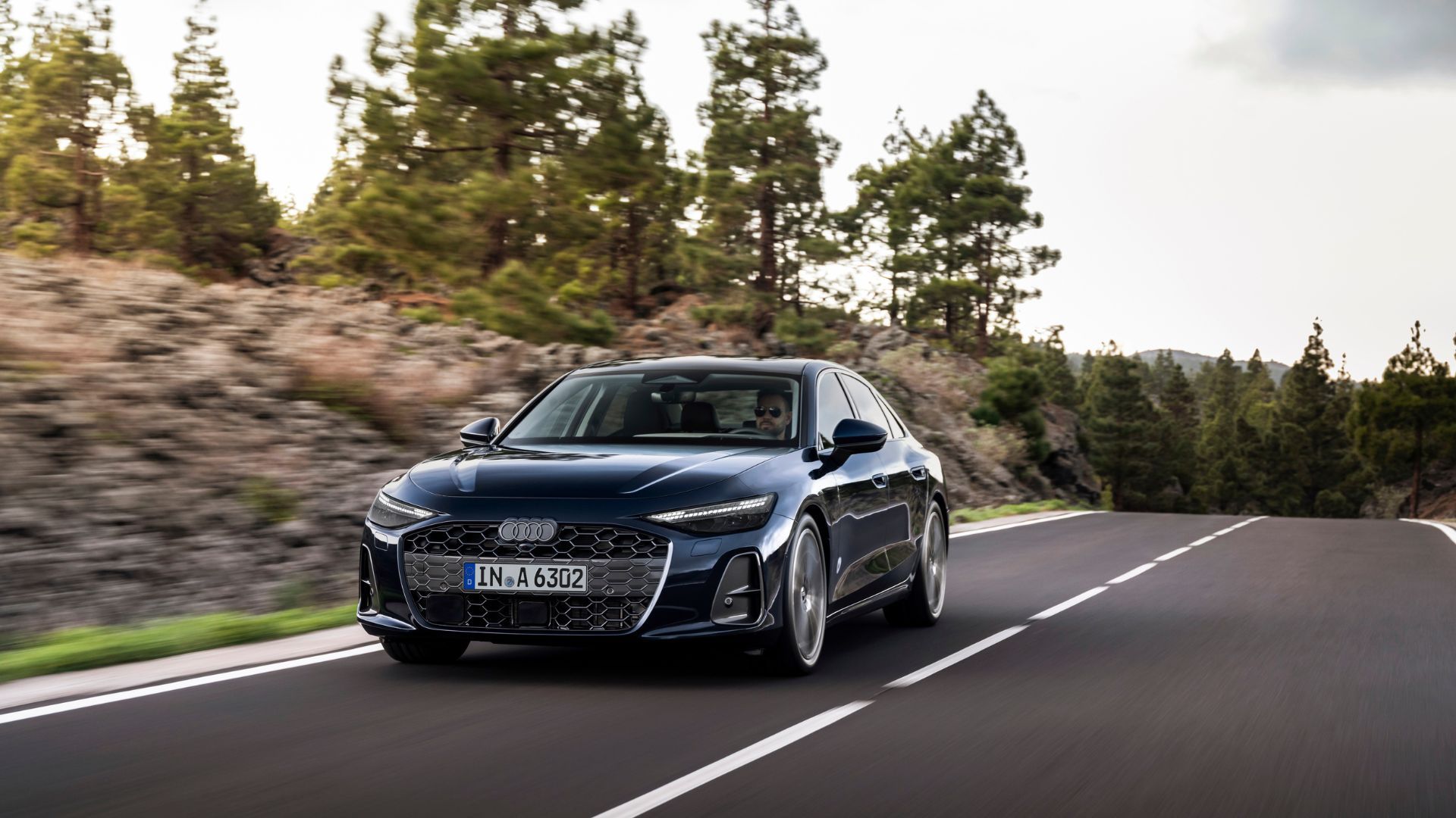 Front 3/4 shot of the all-new Audi A6 Sedan driving on a country road.