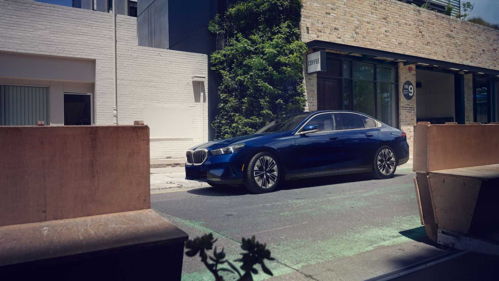 Front 3/4 view of a blue 2024 BMW 5 Series parked outside of a building.