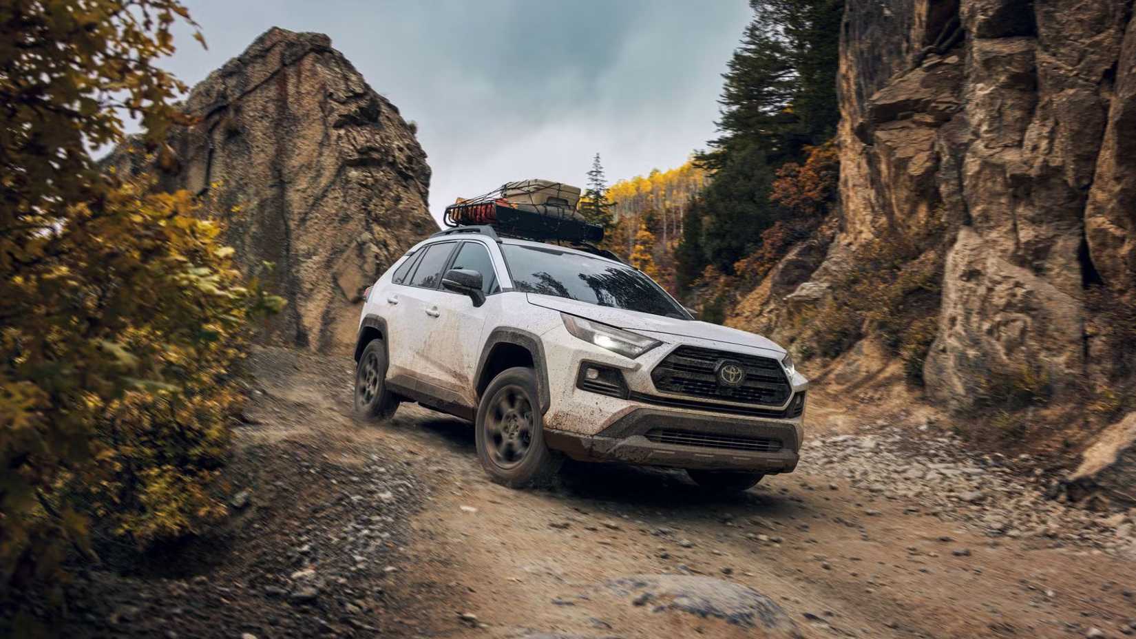 Front 3/4 shot of a white 2024 Toyota RAV4 TRD Offroad off-roading with a large rock in the background.