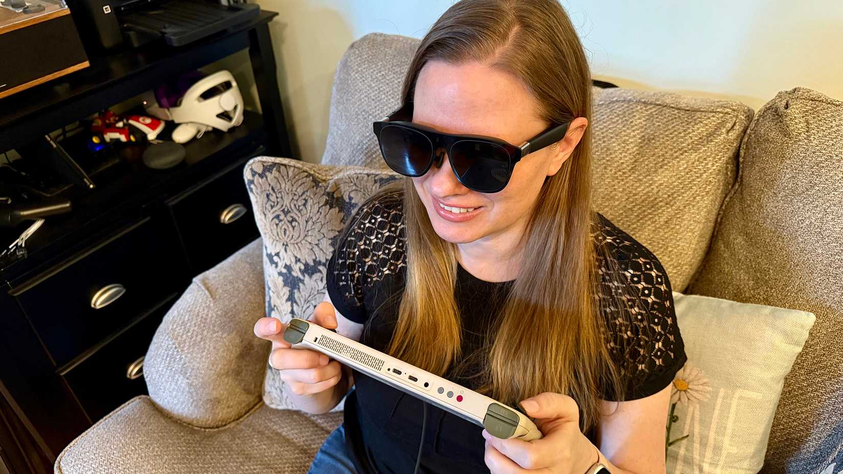 Uma mulher jogando em um PC portátil para jogos enquanto usa os óculos XREAL One AR.