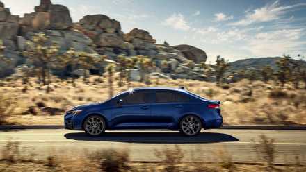 The best gas-powered SUV of 2026 prices not up to you would assume Dynamic side profile shot of a blue 2025 Toyota Corolla Hybrid driving on a country road through the desert.