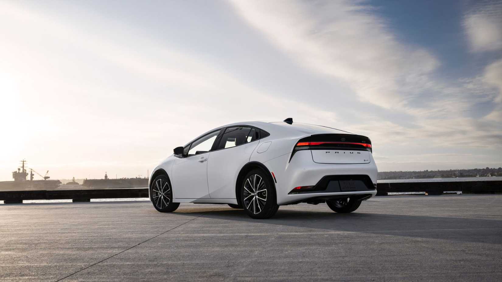 TOMA ESTÁTICA DE 3/4 DE UN TOYOTA PRIUS LIMITADO BLANCO 2025 estacionado con el océano en el fondo.