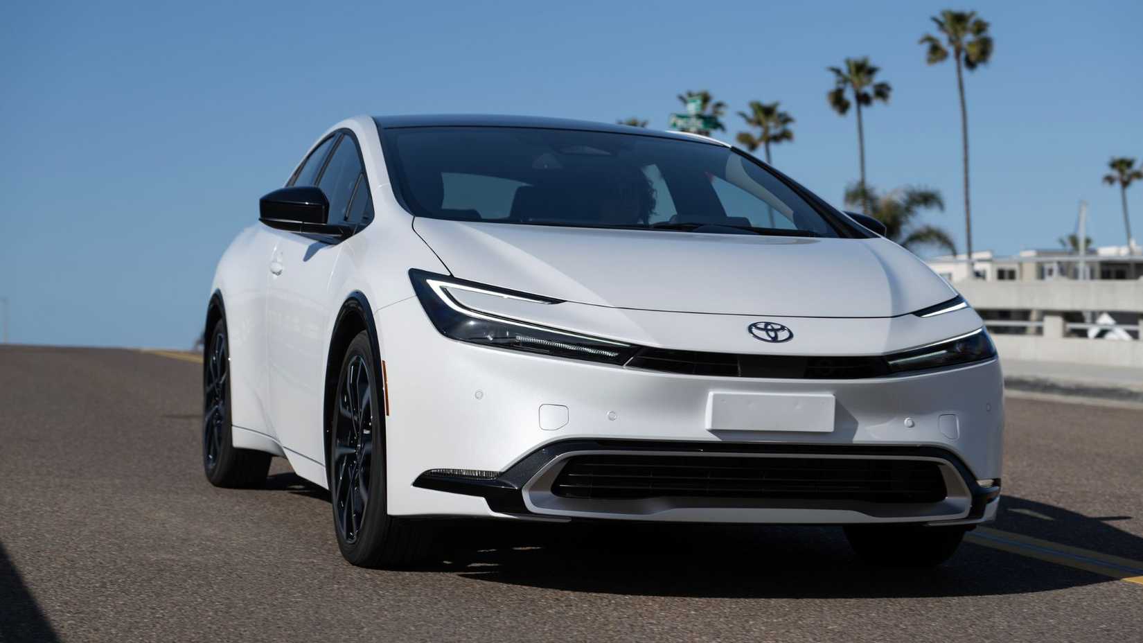 Dynaic front 3/4 shot of a white 2025 Toyota Prius PHEV XSE driving over a bridge.