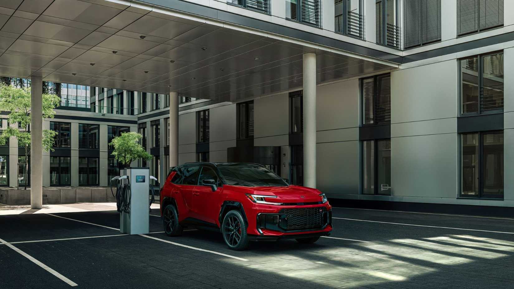 Static front 3/4 shot of a red 2026 Toyota RAV4 PHEV GR Sport charging.