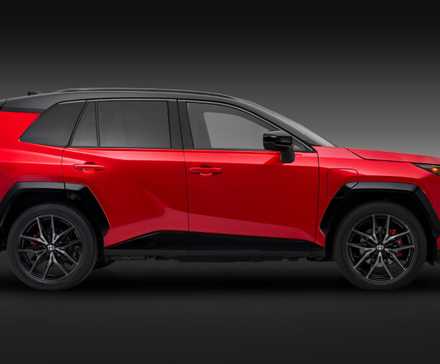 Static side profile shot of a red 2026 Toyota RAV4 PHEV GR Sport in a studio with a black and gray backdrop.