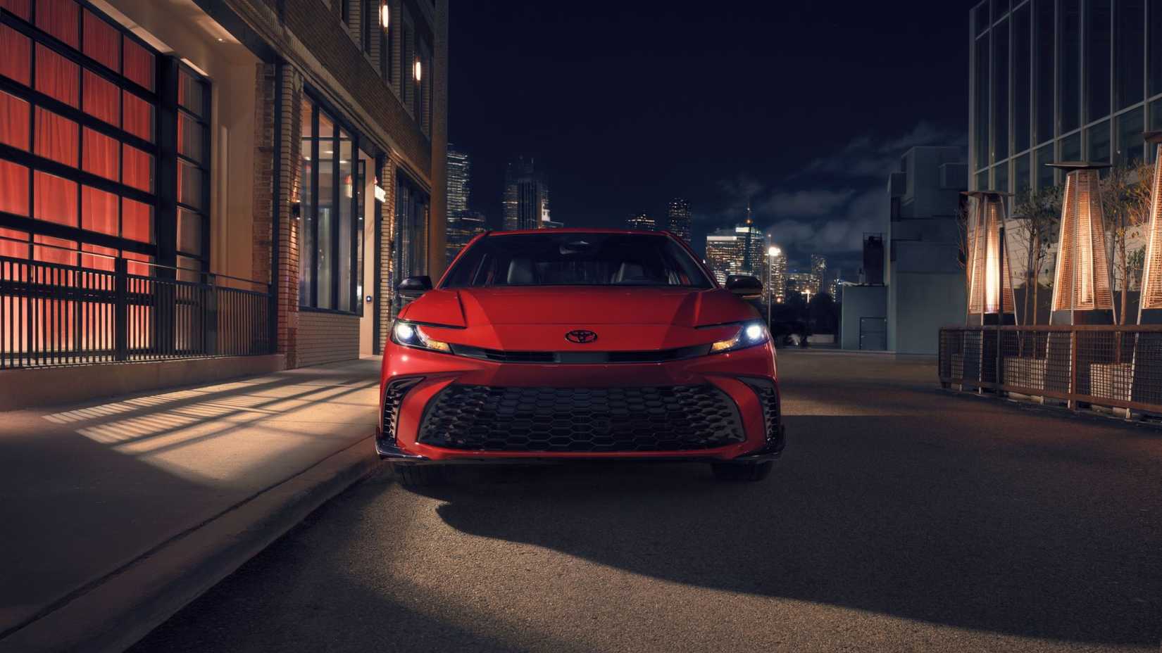 Static front-end shot of a red 2026 Toyota Camry Nightshade in the shadows.