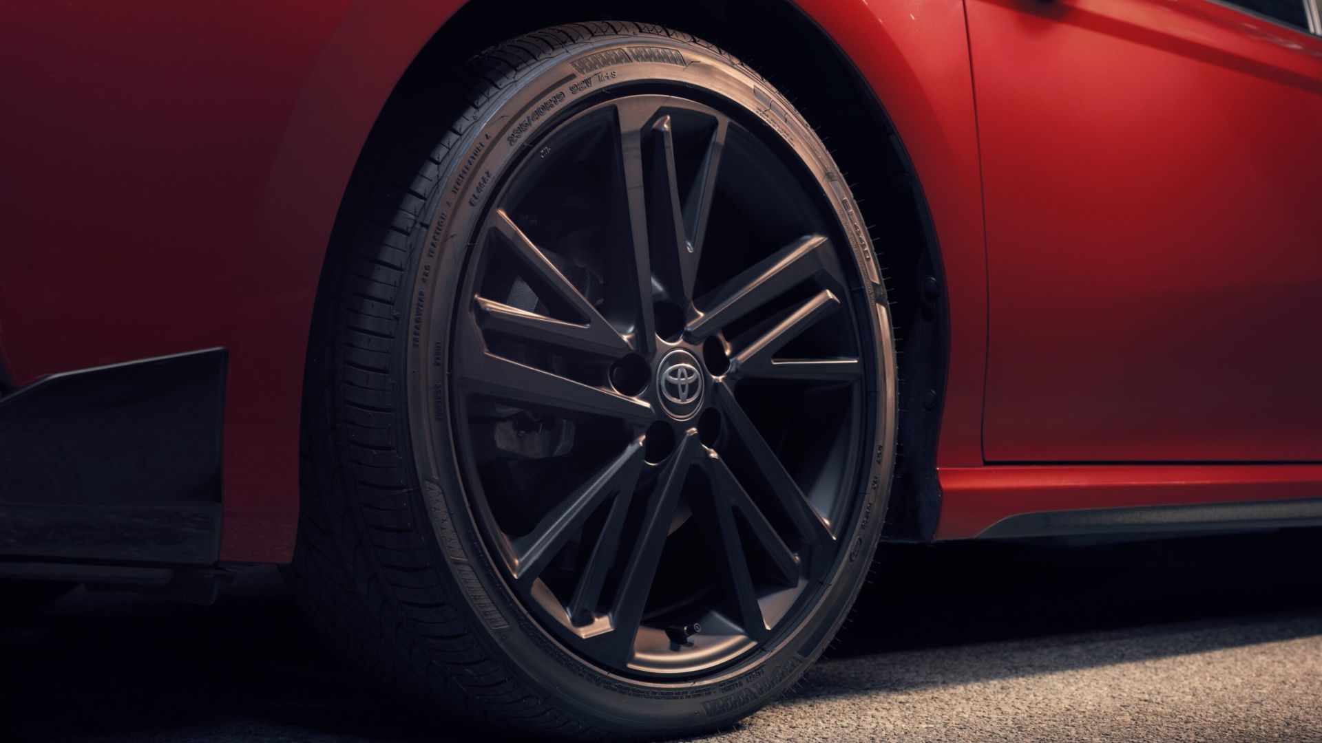 Close-up shot of the black alloy wheel on a red 2026 Toyota Camry Nightshade.