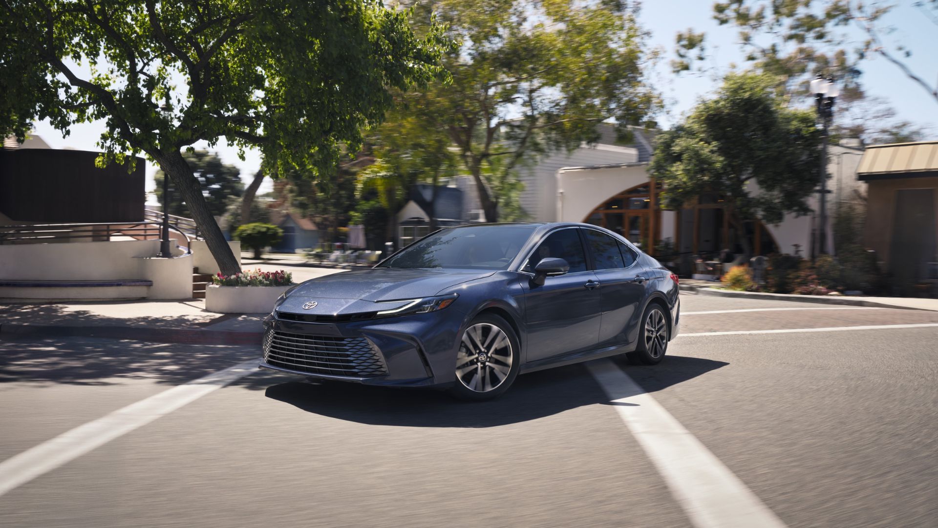 Dynamic front 3/4 shot of a gray 2026 Toyota Camry driving through a city.