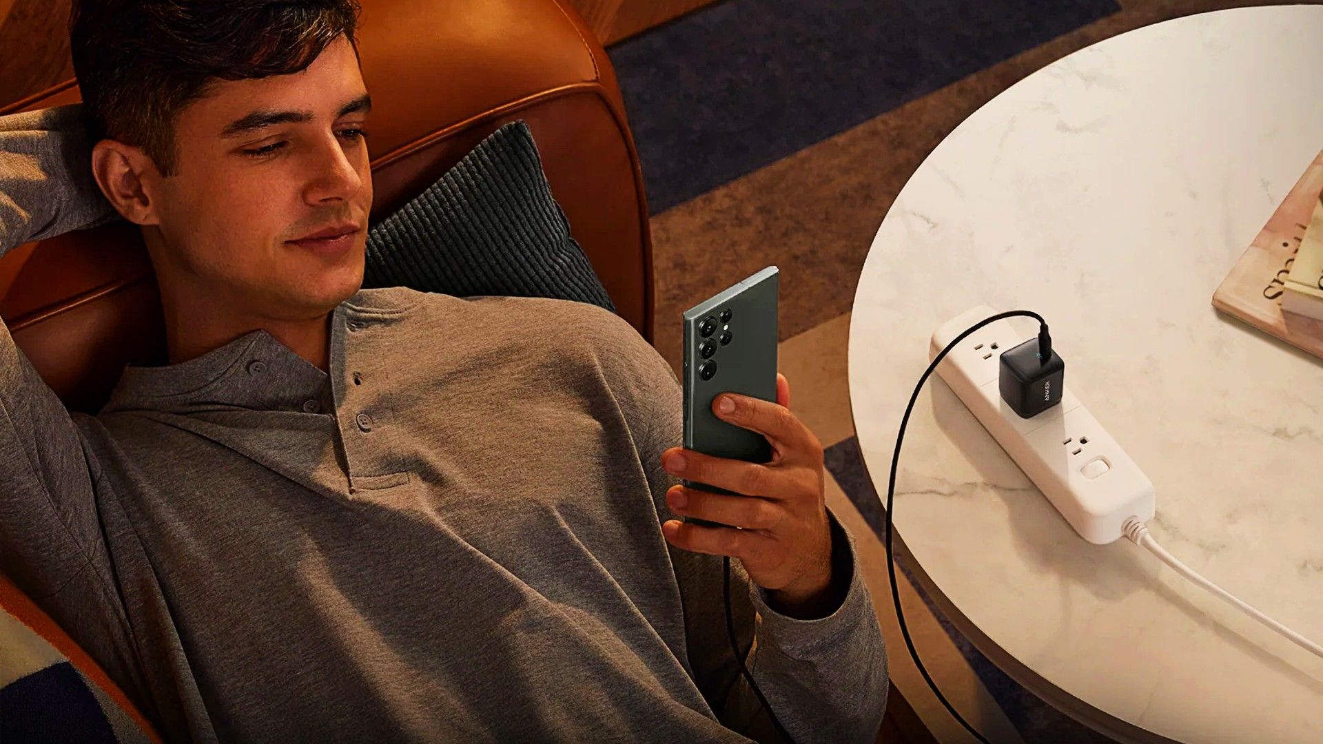 Anker 313 being used to charge a phone while someone uses it.