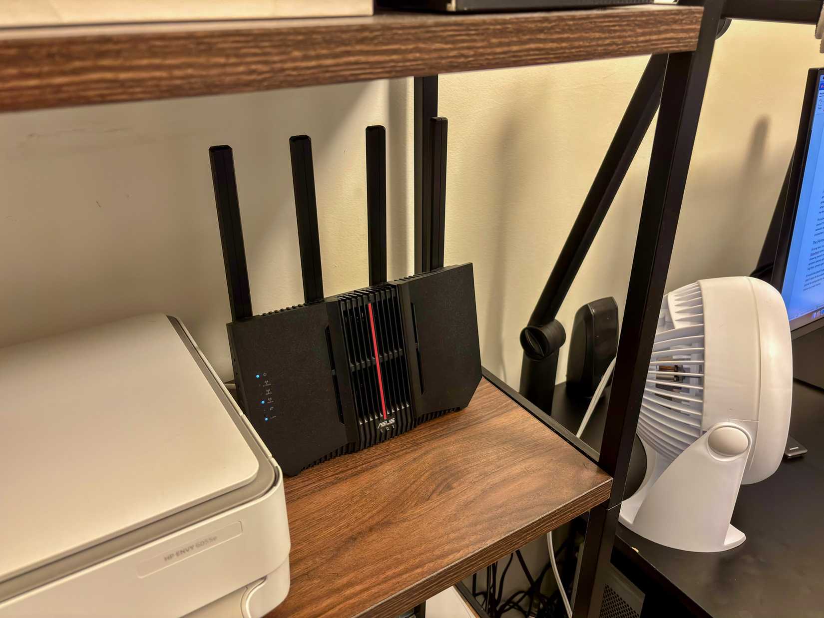 ASUS router on a shelf next to a printer and computer monitor.
