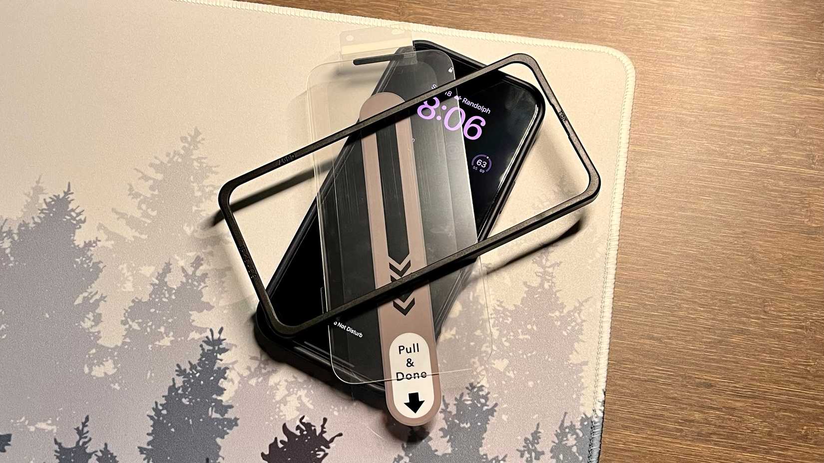 Screen installation protector and frame on an iPhone on a desk mat.