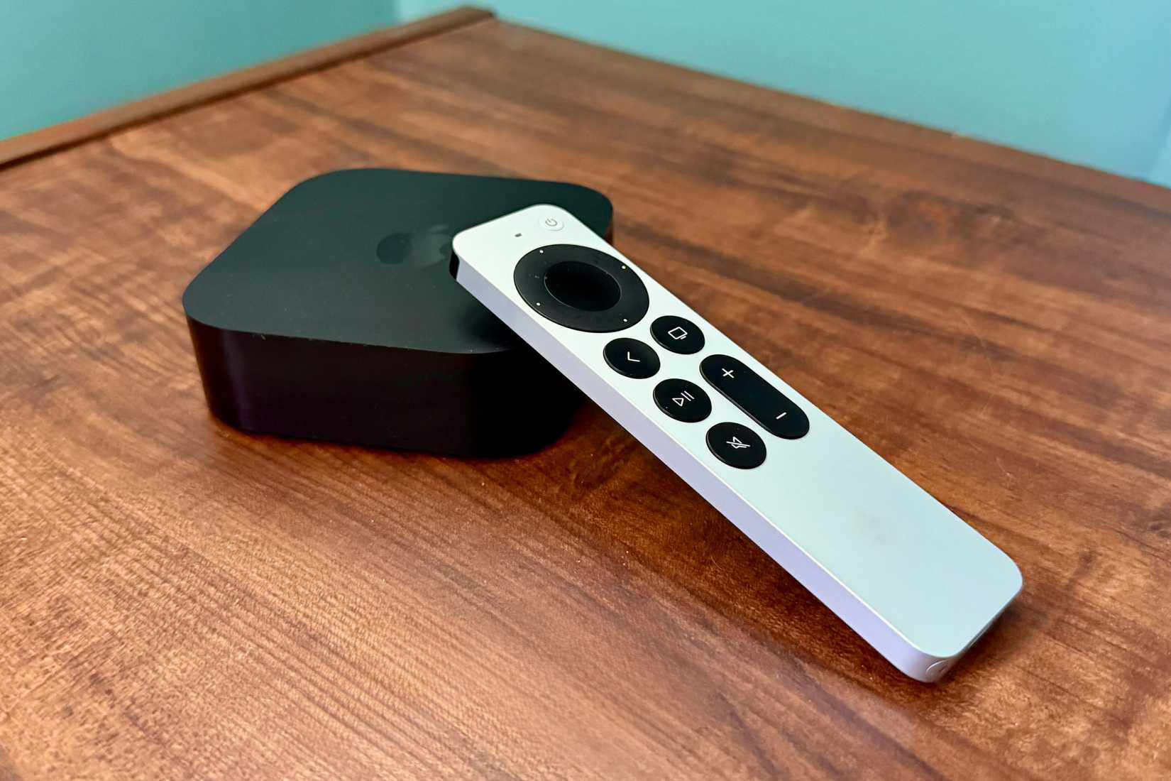 Apple TV 4K e o controle remoto em uma mesa de madeira.
