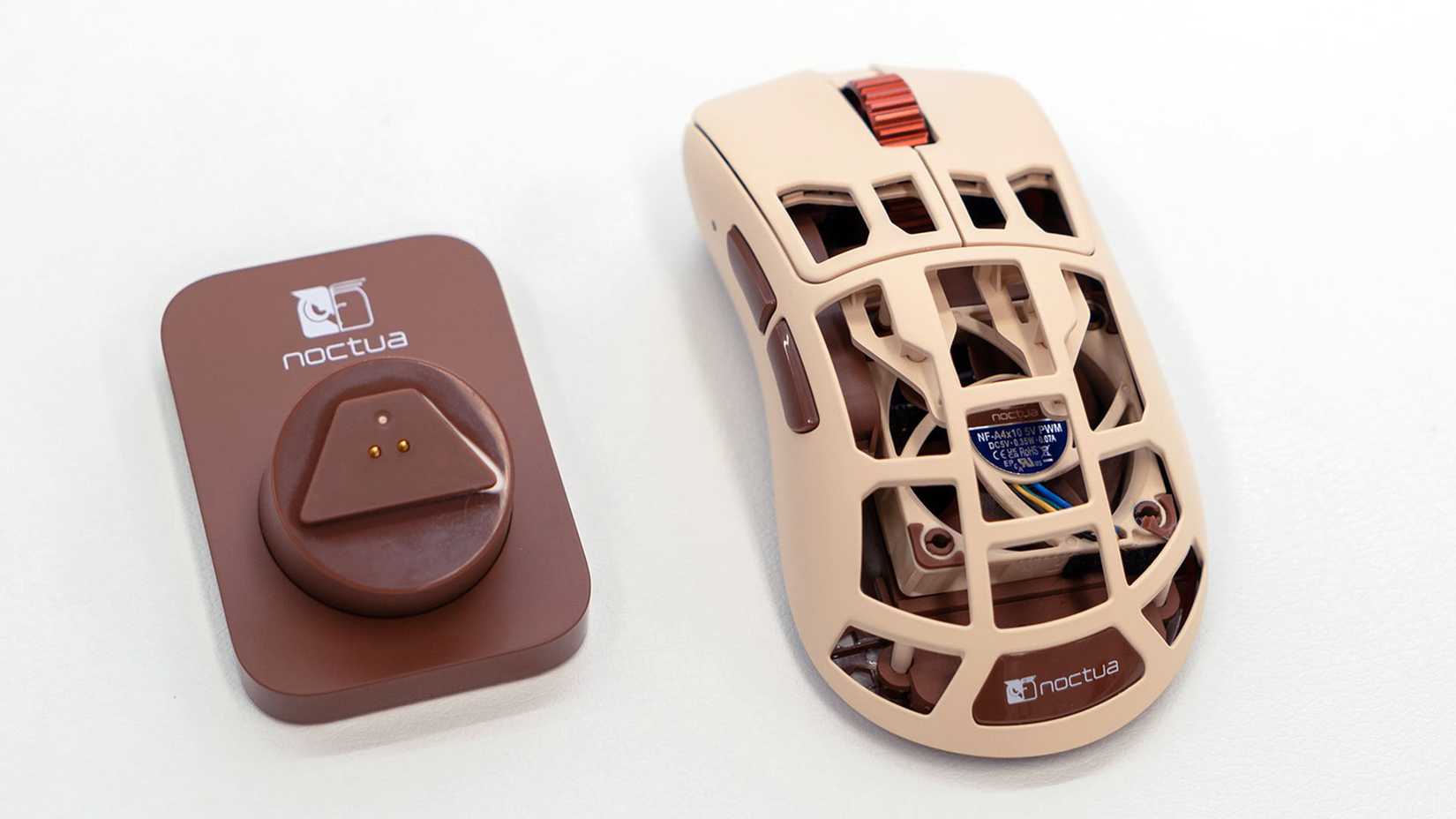 Uma foto mostrando o mouse Pulsar x Feinman Noctua Edition e sua estação de carregamento. 