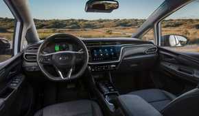Close-up shot inside the cabin of a 2022 Chevrolet Bolt EV, shwoing the front seats, steering wheel, and infotainment screen.