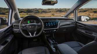 Close-up shot inside the cabin of a 2022 Chevrolet Bolt EV, shwoing the front seats, steering wheel, and infotainment screen.