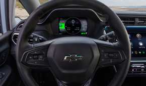 Close-up shot of the steering wheel in a 2022 Chevrolet Bolt EV, showing the digital instrument cluster and infotainment screen.