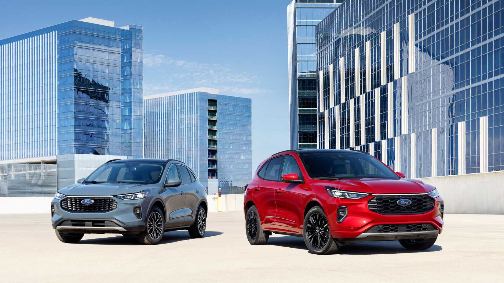 Static shot of two 2023 Ford Escape models—one blue, one red—parked side-by-side with high-rise buildings in the background.