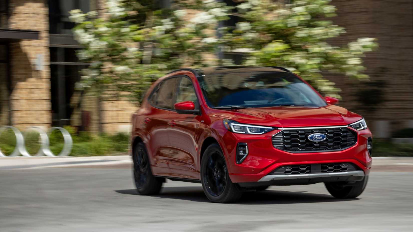 Dynamic front 3/4 shot fo a red 2023 Ford Escape ST-Line Elite driving through a city.
