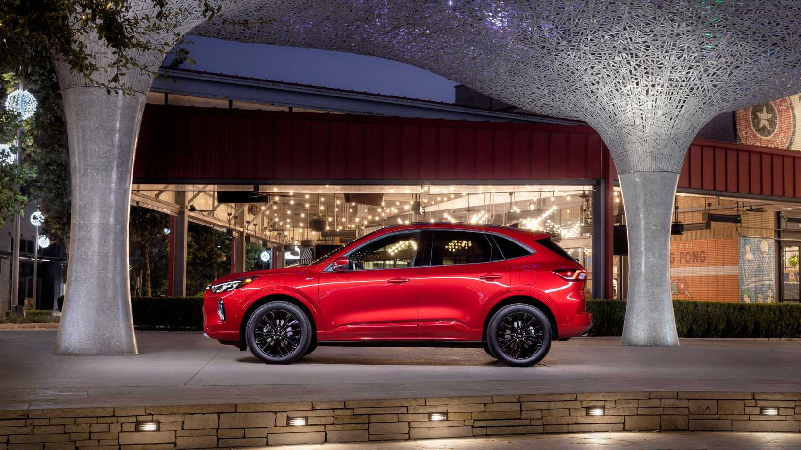 Static side profile shot of a red 2023 Ford Escape ST-Line Elite parked outside of a modern building.
