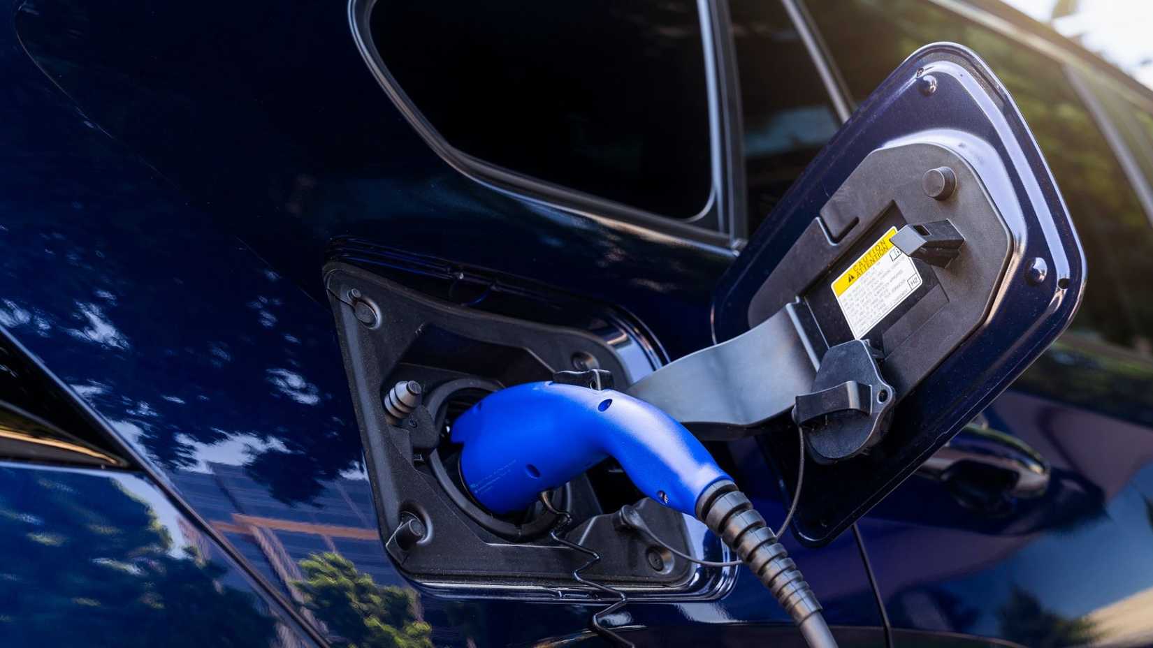 Close-up shot of a a chargign cable plugged into the charging port of a blue 2024 Toyota RAV4 Prime XSE.