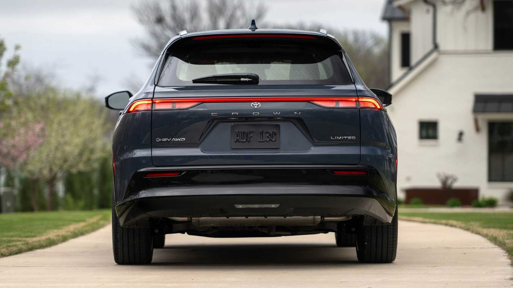 A still shot of the rear of a gray 2025 Toyota Crown Signia Limited parked in a home's driveway.