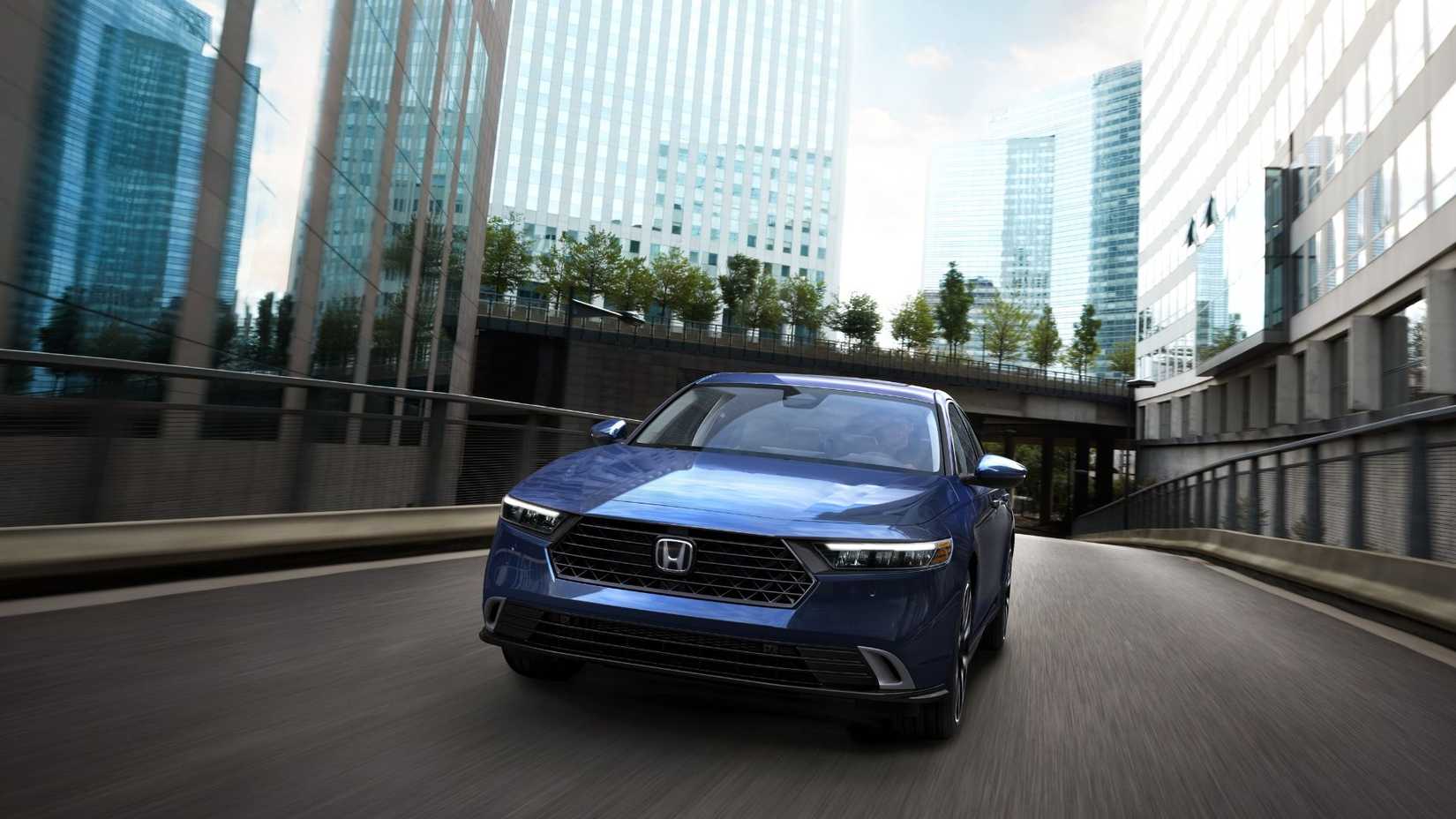 Dynamic front-end shot of a blue 2023 Honda Accord Touring driving through a city.