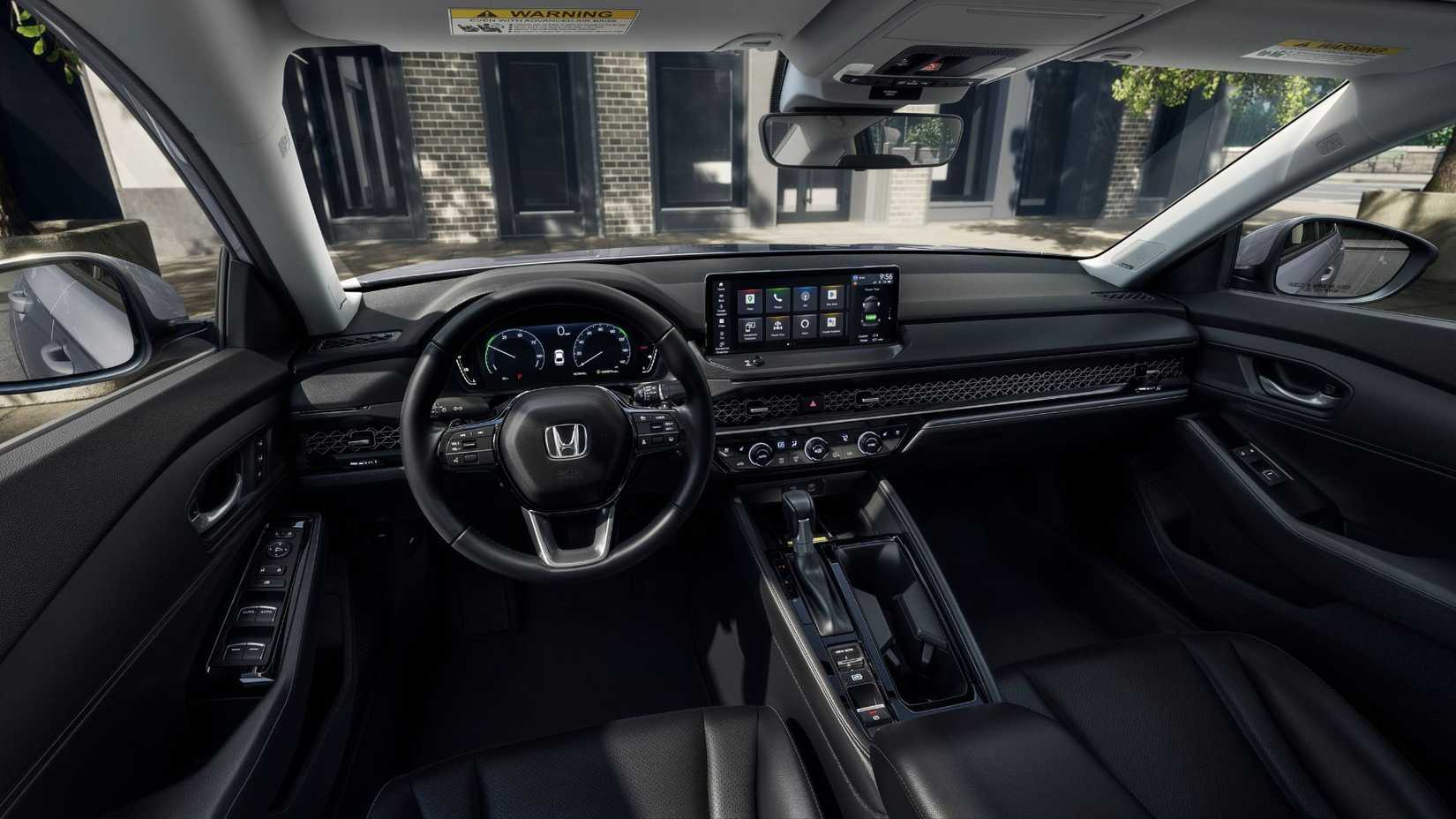 Shot inside the cabin of a 2023 Honda Accord Touring, showing the front seats, steering wheel, and infotainment screen.