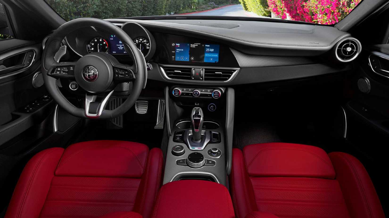 Close-up shot of the cabin of a 2022 Alfa Romeo Giulia, showing the red leather frotn seats, steering wheel, and infotainment screen.