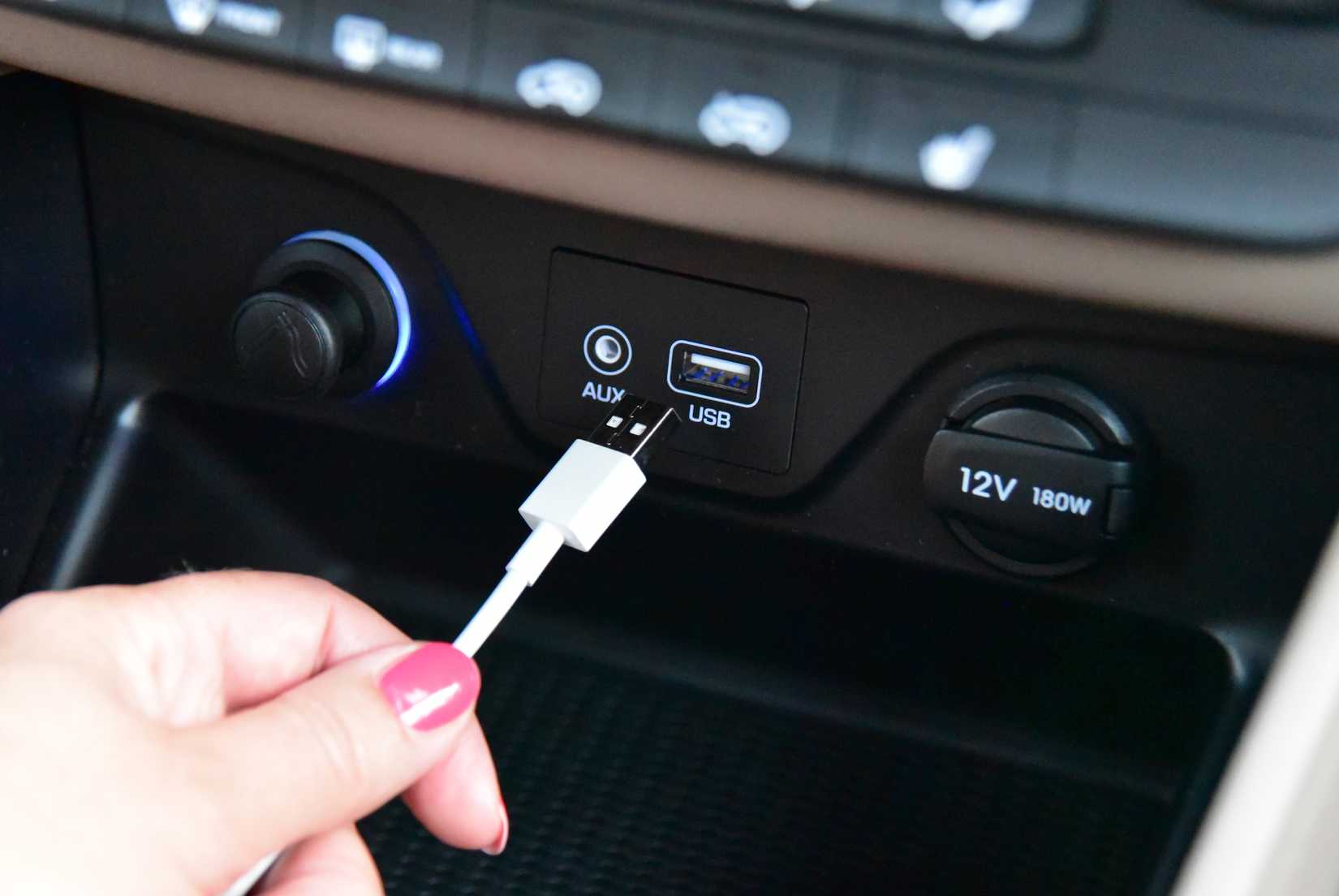 Manually connecting a USB cable to a port on a car's dashboard