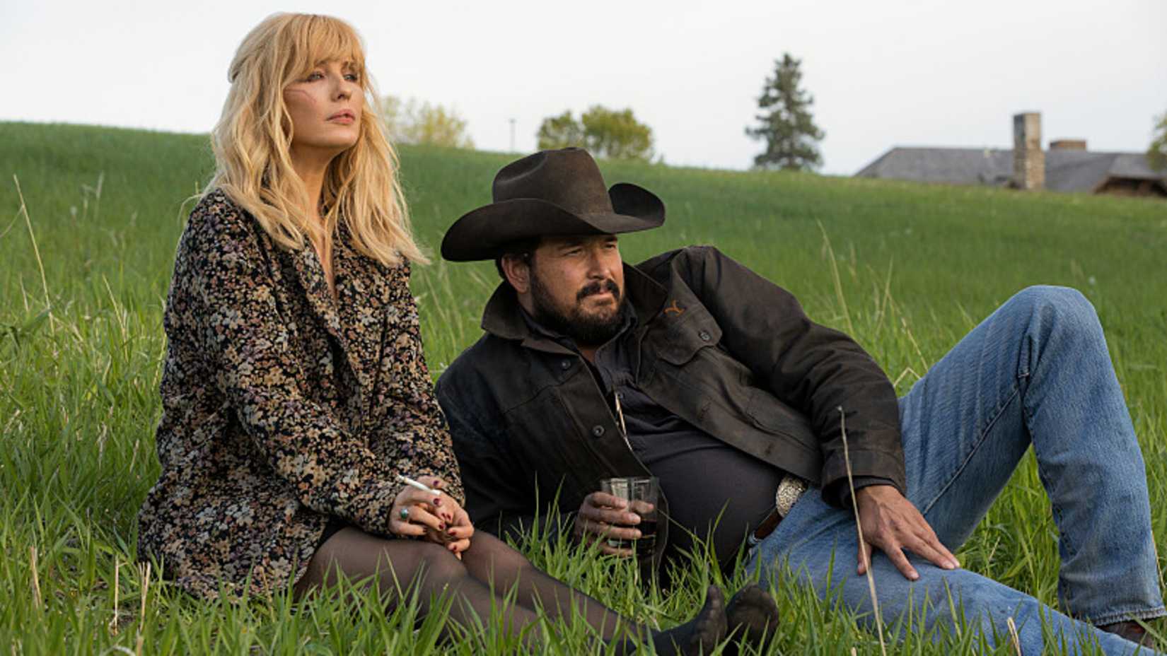 Yellowstone's Beth and Dutton Rip Wheeler sitting in the grass.