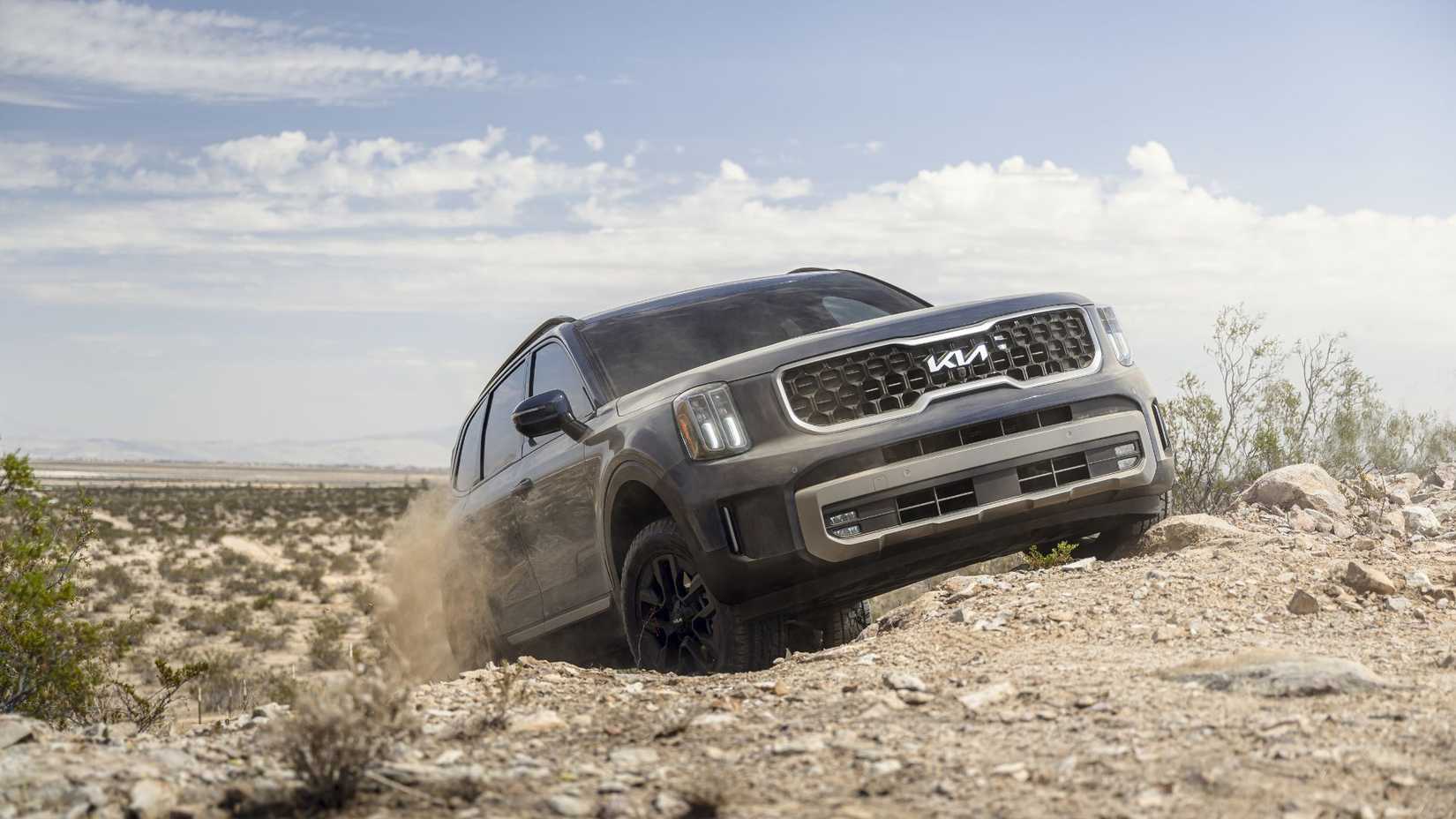 Dynamic front 3/4 shot of a blue 2023 Kia Telluride off-roading in the desert.