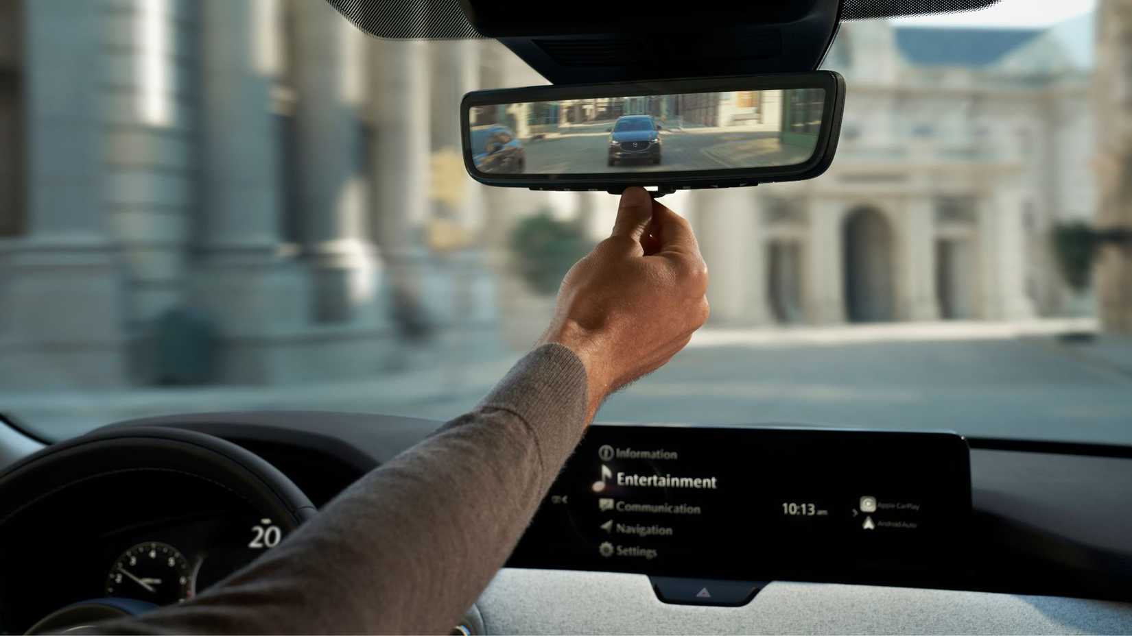 Close-up shot of a driver adjusting the digital rearview mirror in a 2025 Mazda CX-90.