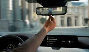 Close-up shot of a driver adjusting the digital rearview mirror in a 2025 Mazda CX-90.