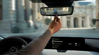 Close-up shot of a driver adjusting the digital rearview mirror in a 2025 Mazda CX-90.