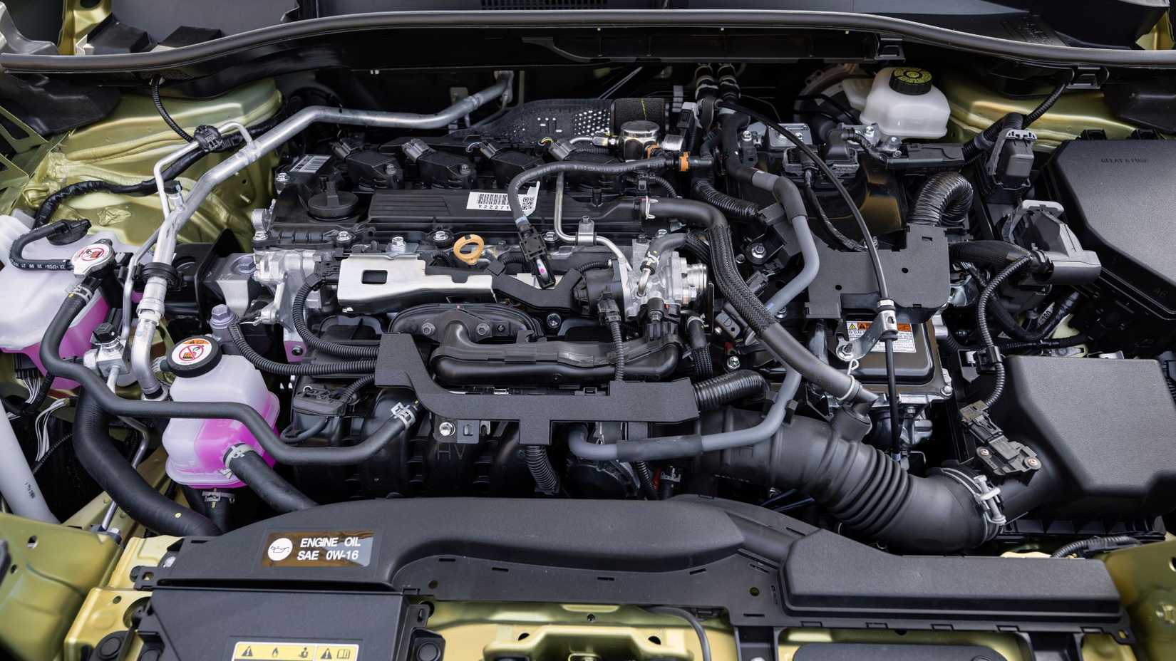 Close-up shot under the hood of a 2024 Toyota Corolla Cross Hybrid XSE, showing the 2.0-liter inline-4 engine with battery pack.