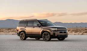 Static front 3/4 shot of a bronze 2025 Hyundai Santa Fe Hybrid parked on a salt plain with mountains in the background.